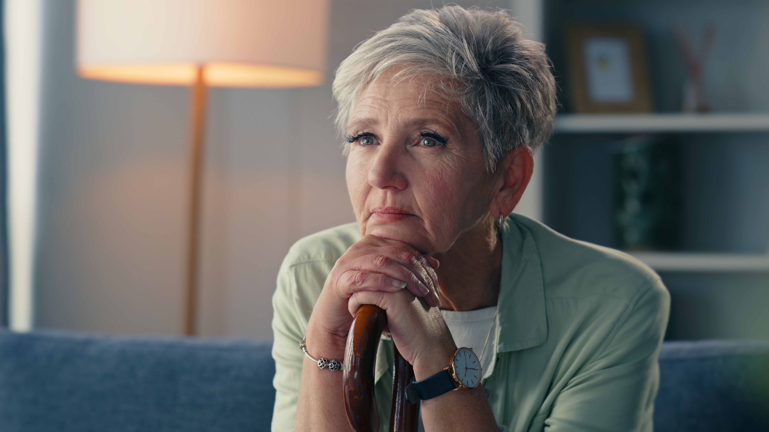 An older woman rests her chin on her hands as she thinks about something serious.