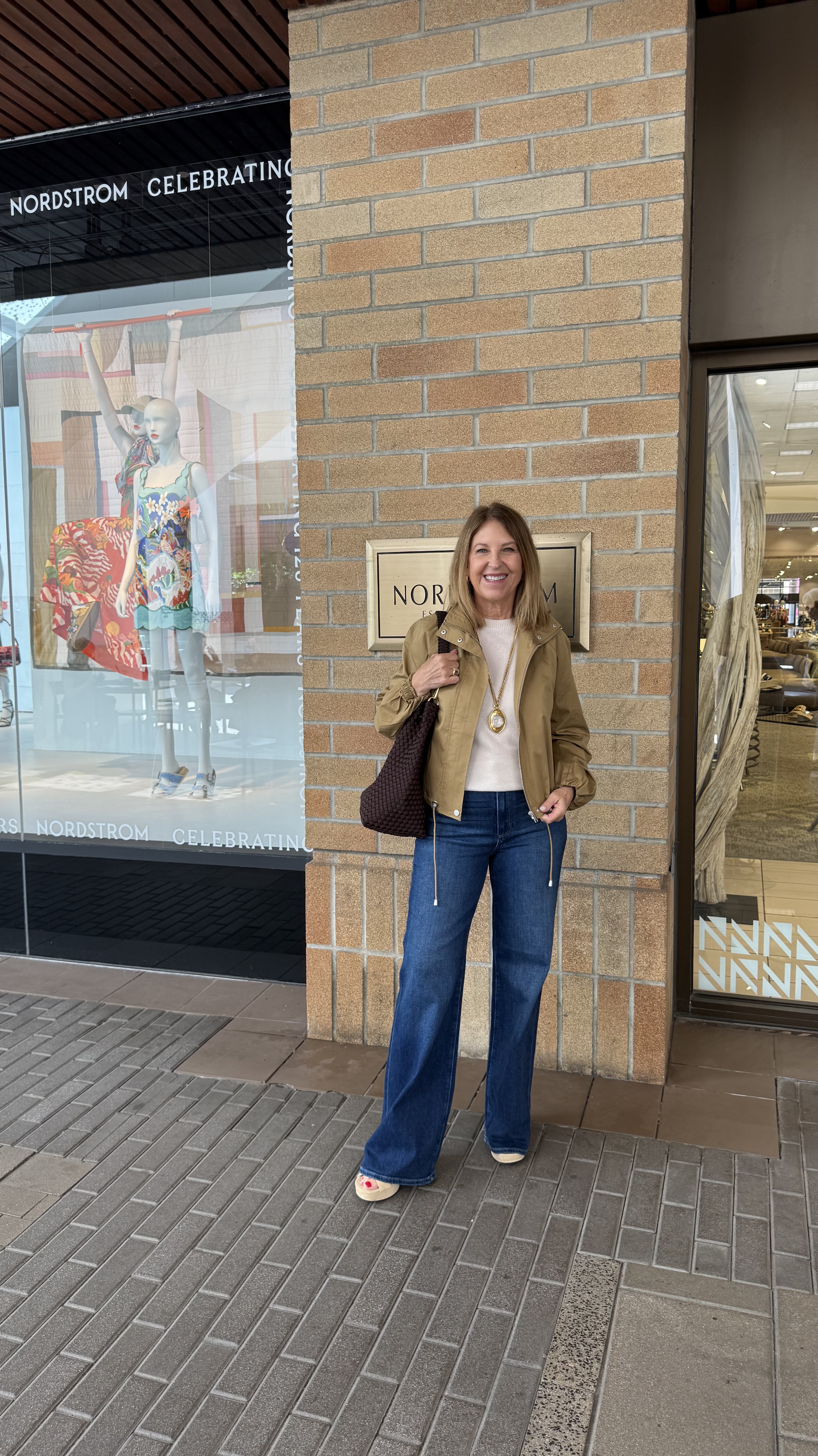 Sandy Koszarek wearing a tan jacket, a white tee, and jeans.