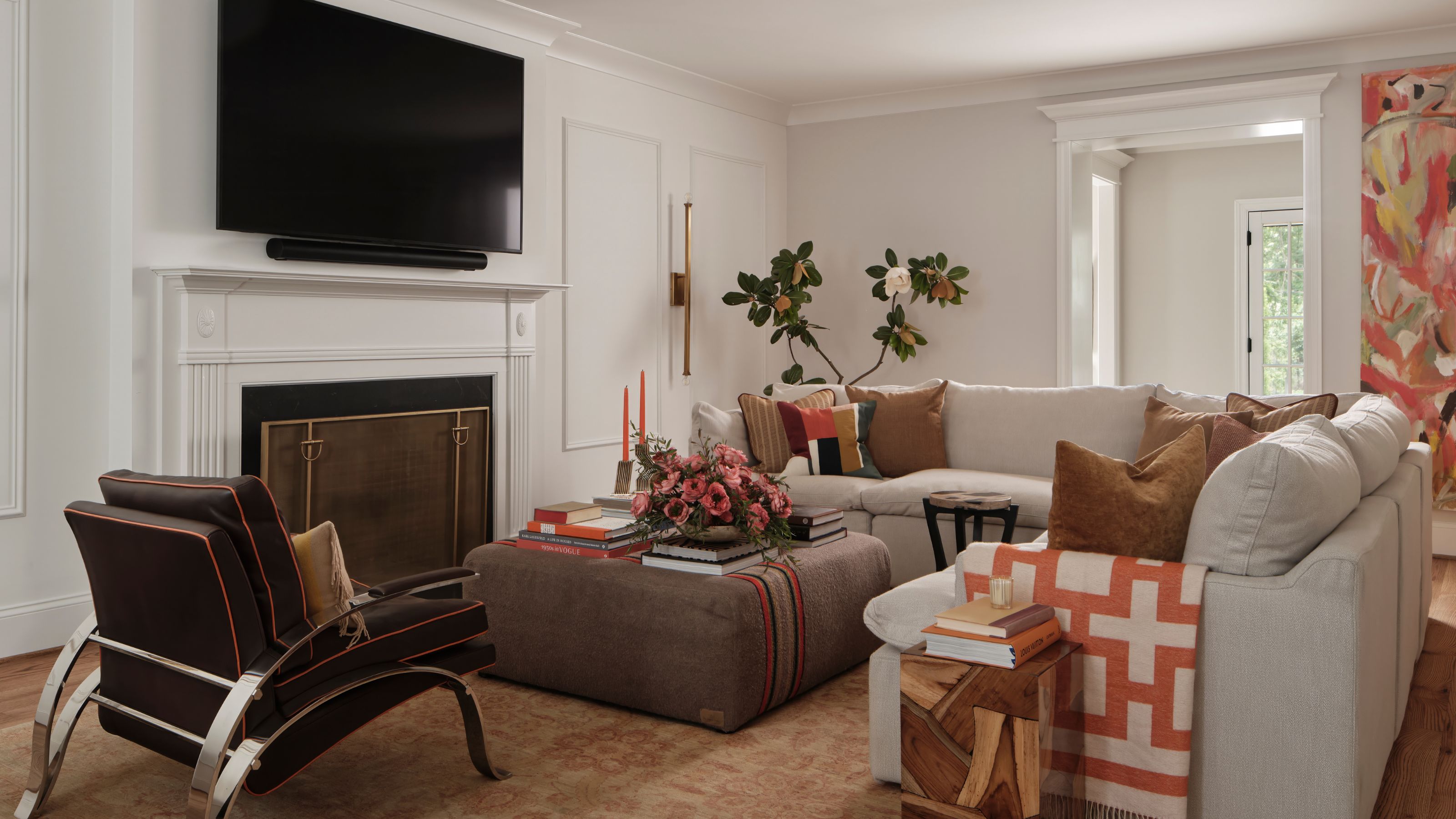 neutral and warm living room with brown and terracotta color injections, a white fireplace, with a large TV hung above