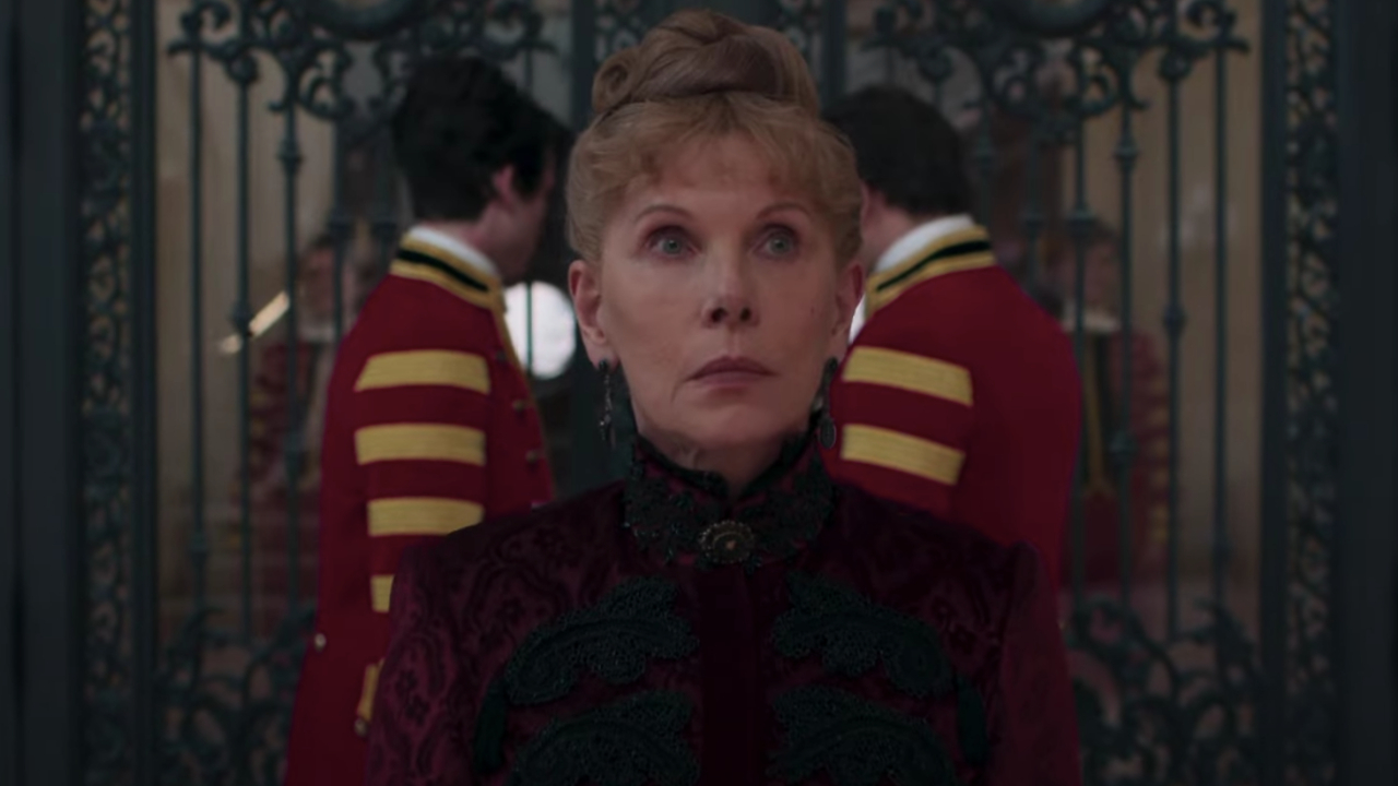 Christine Baranski stands solemnly in front of a set of gates in The Gilded Age.