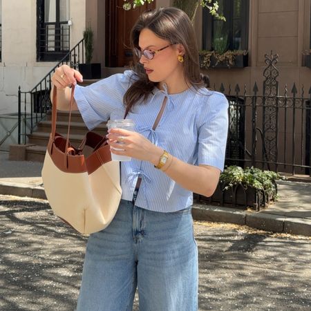 @maggie_mccormack wears a blouse and blue jeans. 