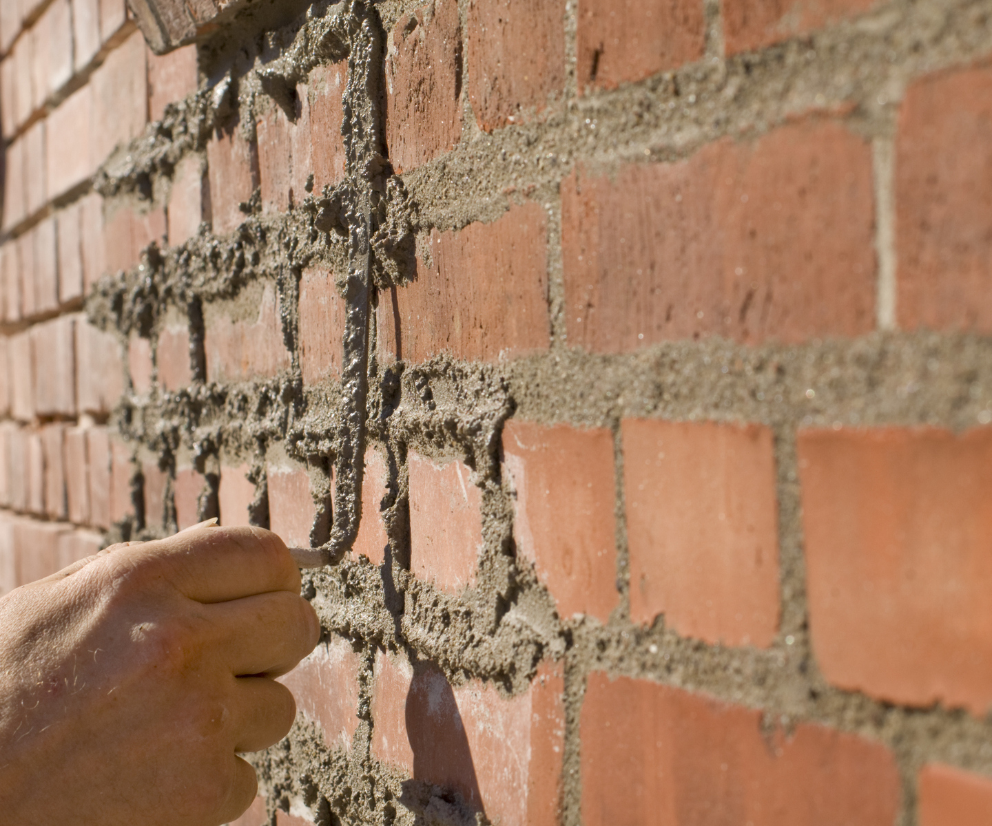 A bricklayer repointing brickwork with fresh mortar