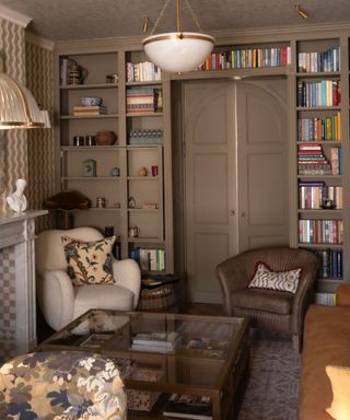 small living room painted in farrow and ball mouse's back with custom shelving surrounding the door concealing a hidden tv