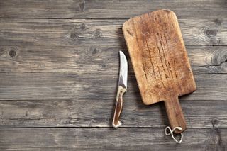 Old chopping board with knife on wooden table