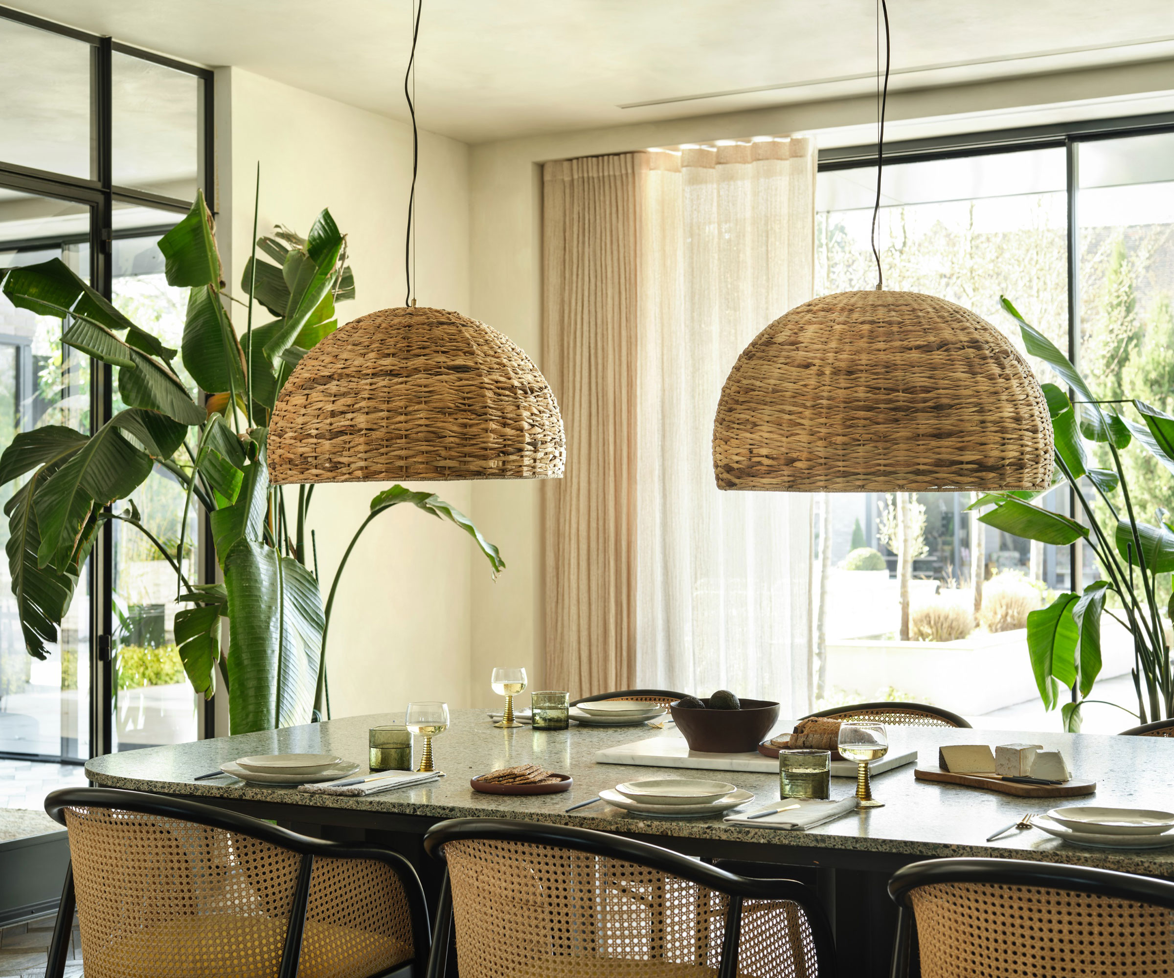 pair of oversized rattan pendant lights over dining table