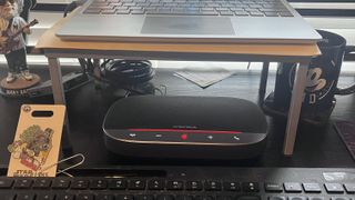 The AnkerWork SR500 set up on a home desk with the red light LED beaming indicating the speakerphone is muted. 