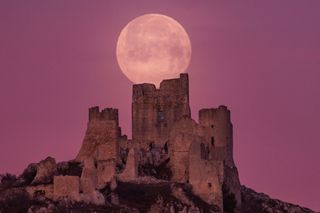A full moon rises over castle ruins in Italy