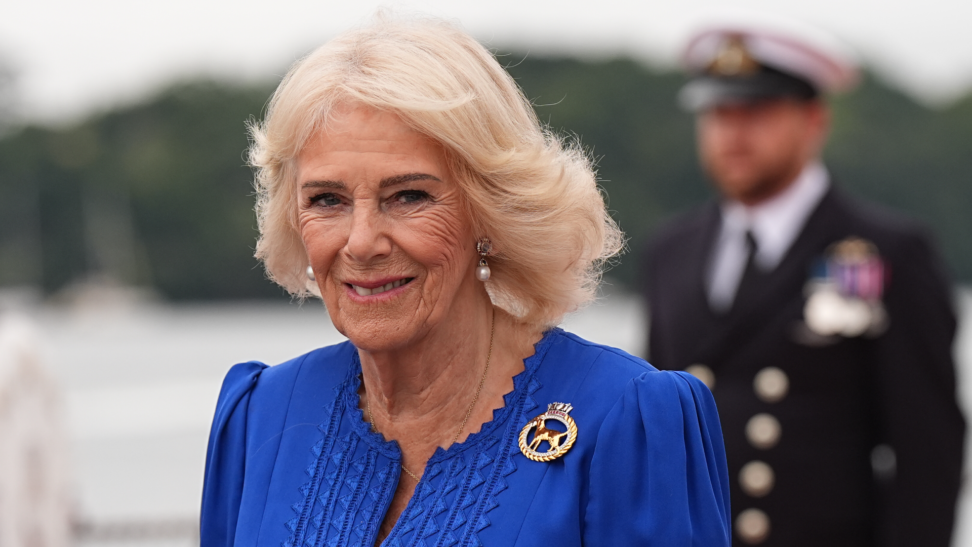 Queen Camilla wearing a blue dress and smiling