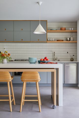 Kitchen with concrete floor, grey-blue cabinets and white and wood island