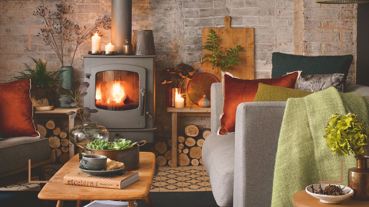 Cosy living room with a log burner in a brick open fireplace with grey armchairs on either side to show how to keep your house warm in winter 