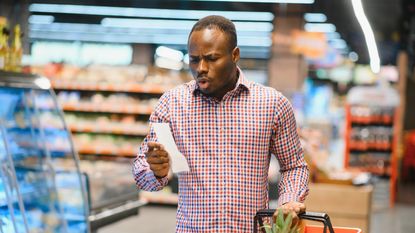 A man looks surprised as he looks at his grocery store receipt.