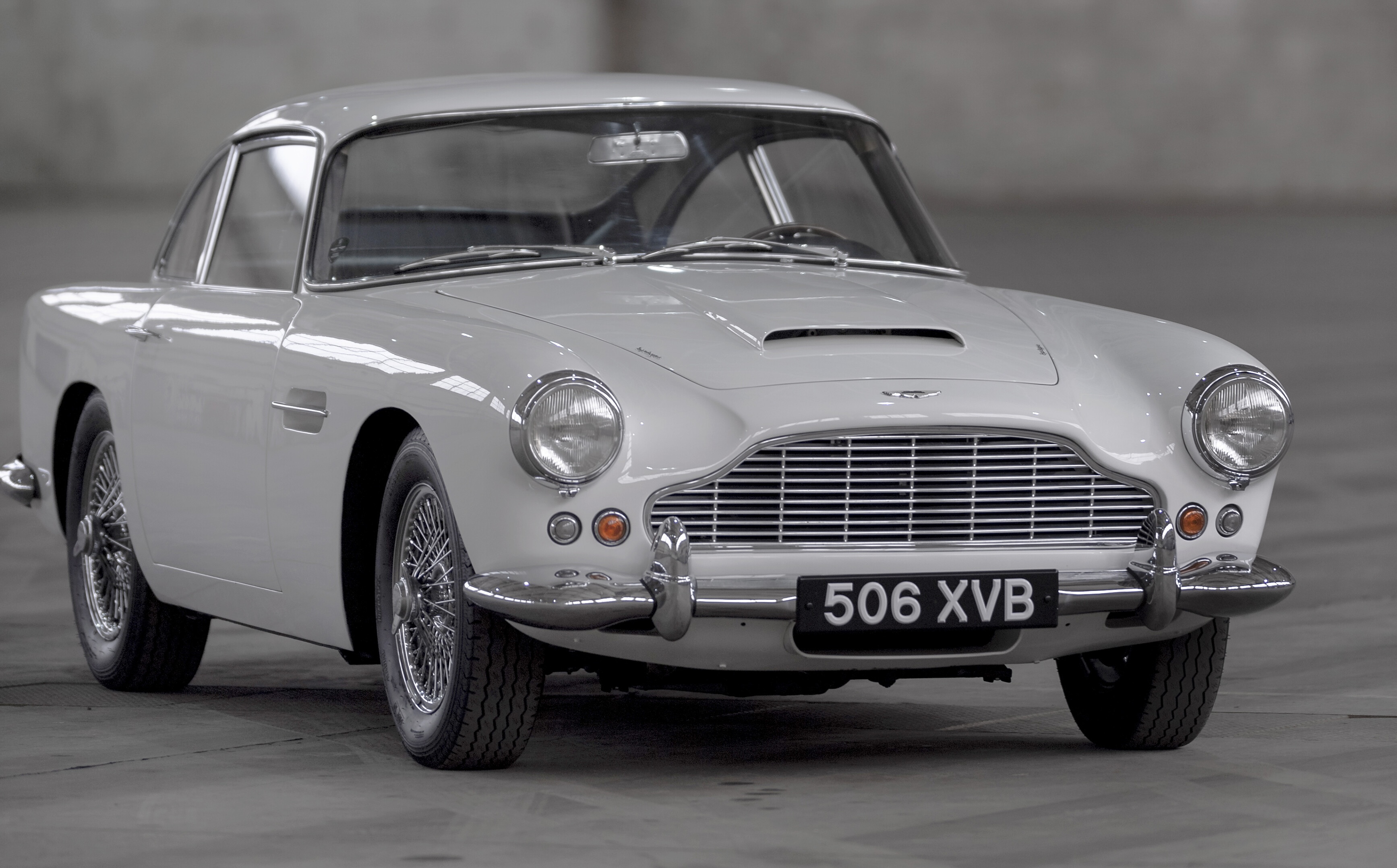 Details of the Aston Martin DB4, painted white, in a grey airplane hangar
