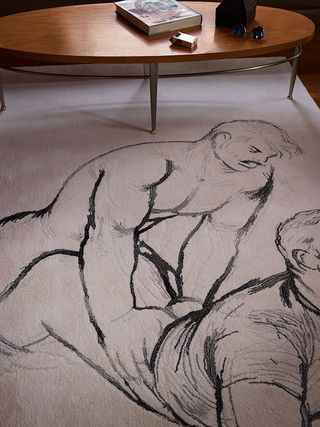Large white floor rug with male erotic artist sketch in charcoal, wooden oval coffee table, with silver metal legs, book, sunglasses, open packet of cigarettes, brown ornament