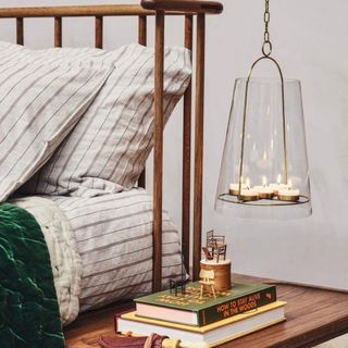 Wooden bedhead with a built in bedside table and glass lampshade containing tea light candles suspended to the side.