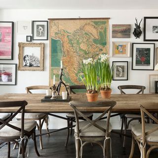 white dining room with wooden dining table and chairs and gallery wall with vintage map