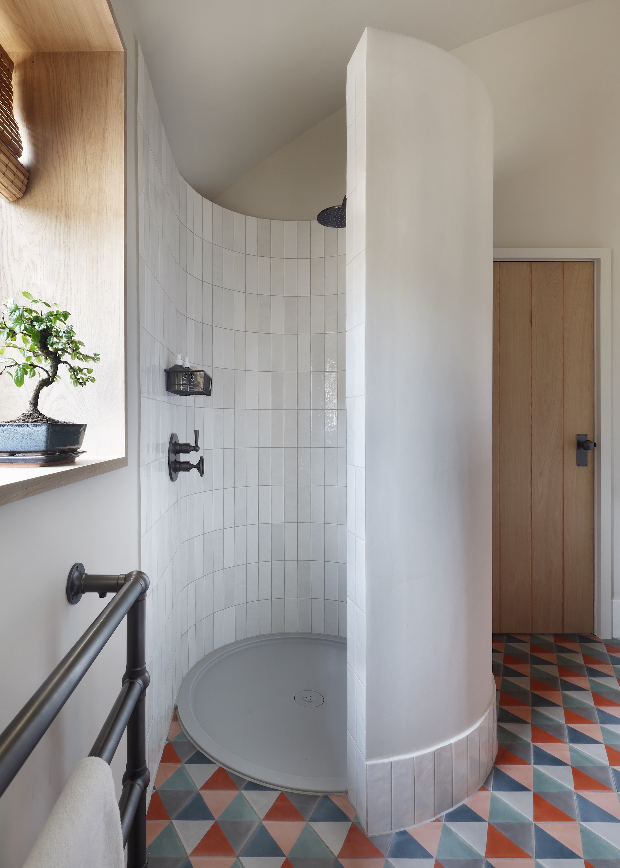 shower with open curved enclosure and triangle floor tiles