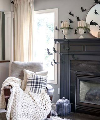 Living room with mantel decorated with paper bat decorations, cozy armchair