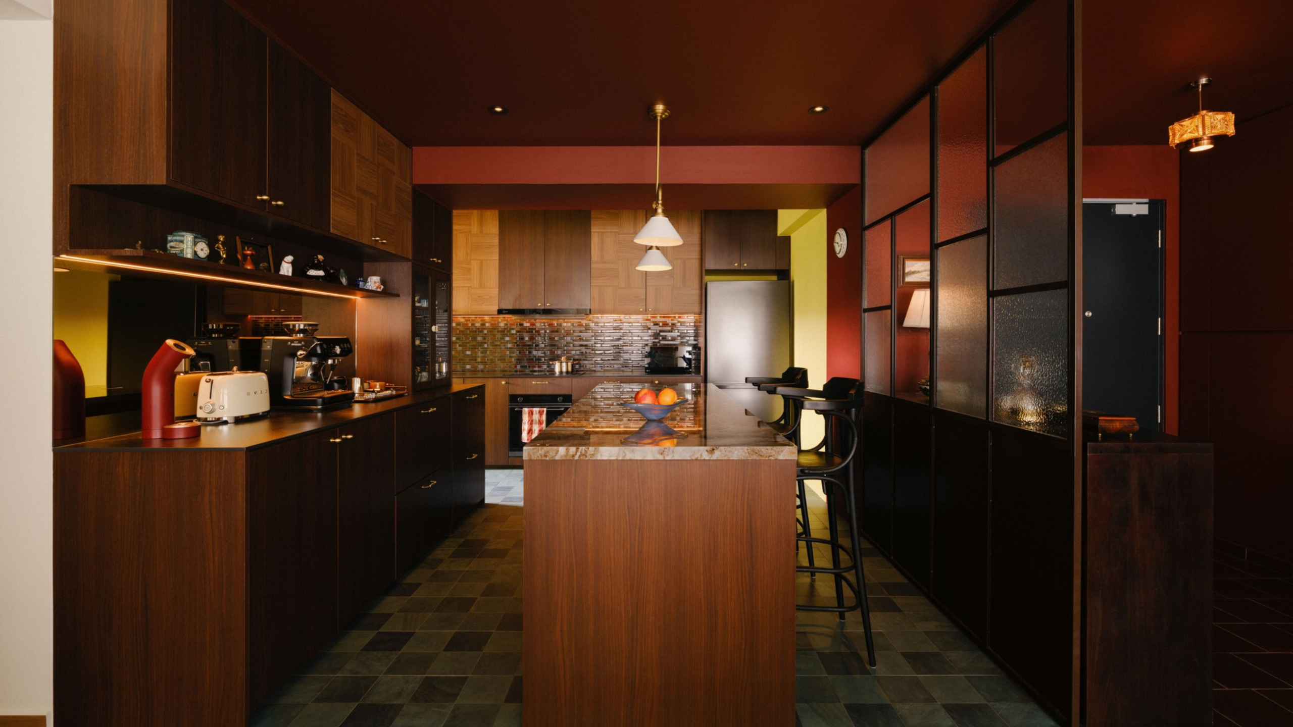 a deep red compact kitchen with butter yellow accents and timber cabinetry
