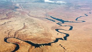 aerial view of lake powell with low water level with desert surrounding and mountains behind