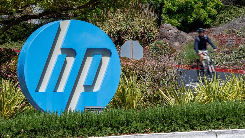 HP logo pictured on a sign at the company headquarters in Palo Alto, California, with cyclist passing by in background.