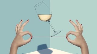 women's hands holding string balancing wine glass against blue background