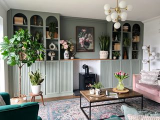 A living room with a built in bookcase painted in sage green