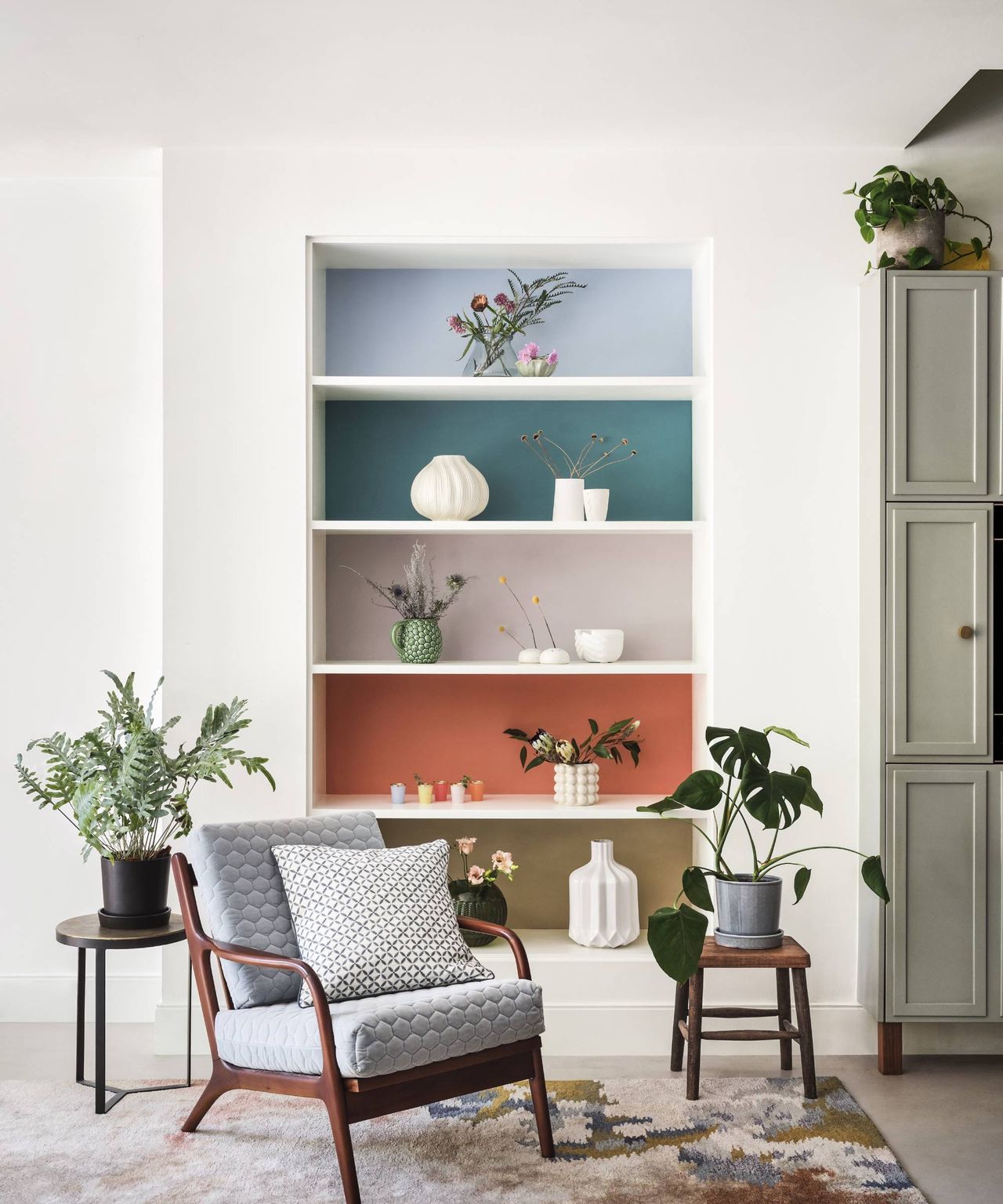 living room with white walls, white alcove shelving and different colour painted at the back of each shelf