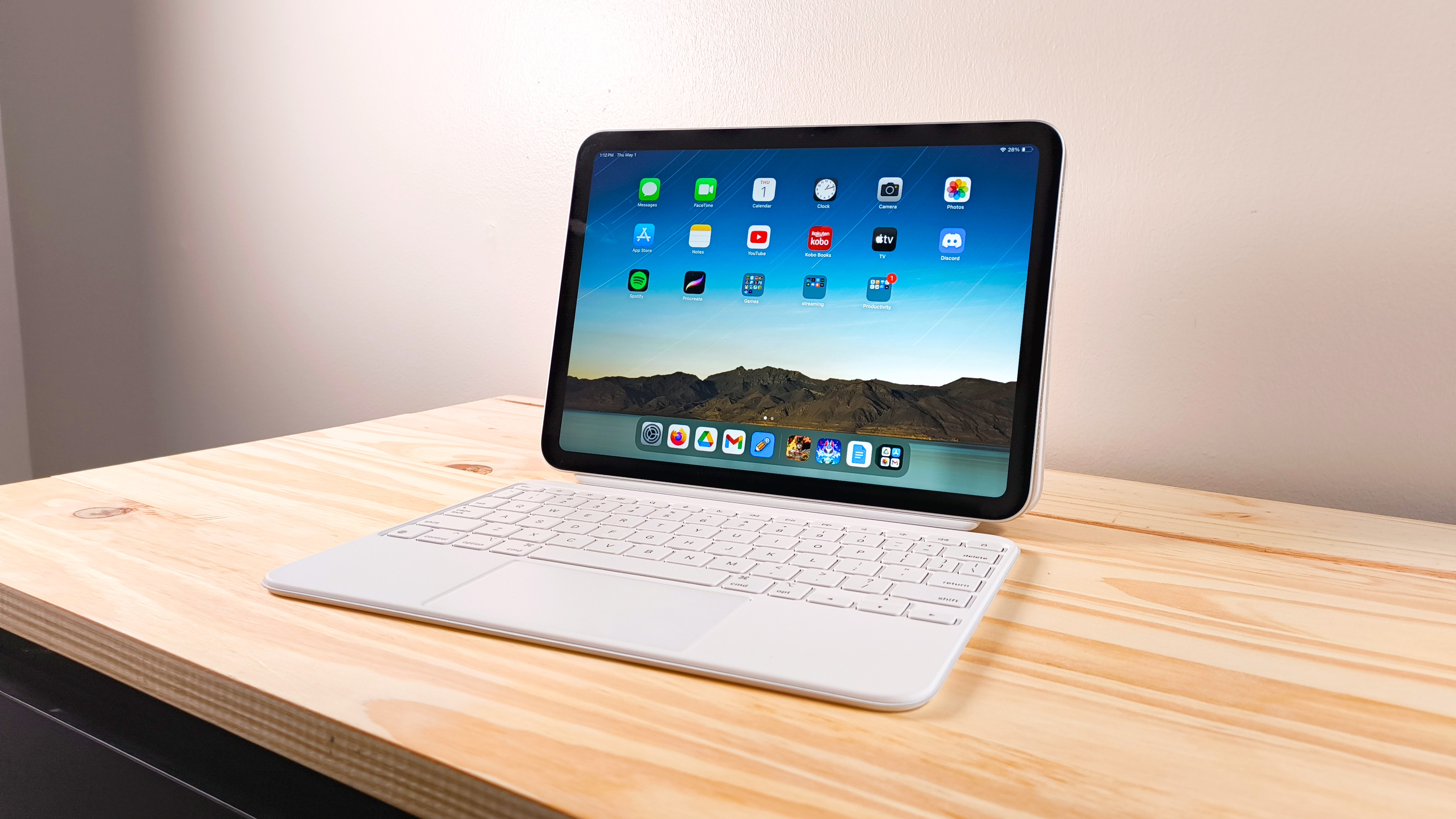The iPad 11 propped up on a wood table connected to the Magic Keyboard Folio