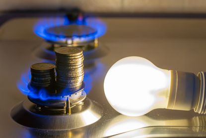 Light bulb on next to lit gas cooker, with coins next to it