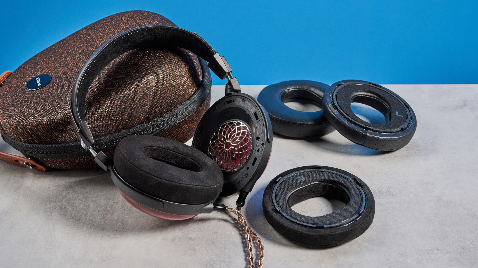 the fiio ft13 wired headphones with wood cups and copper cable photographed against a blue background