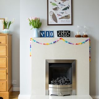 White living room with minimalist fireplace decorated with rainbow pompom garland
