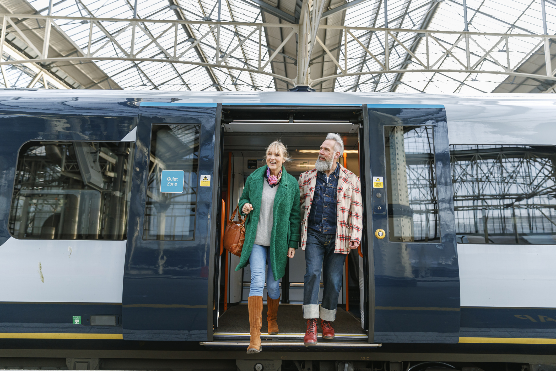 A stylish senior couple exits a train at the train station while vacationing in the city.
