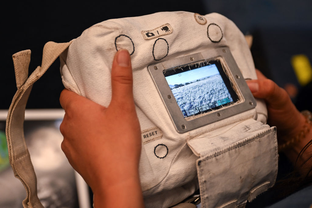 An attendee looks at photographs made with the Handheld Universal Lunar Camera, which is designed incorporating a modified Nikon Z9 and a protective cover and grip, during a media event for NASA's Joint EVA and Human Surface Mobility Test Team Field Test 5 (JETT5) to practice moonwalking operations for the Artemis lunar missions to the Moon in Flagstaff, Arizona on May 18, 2024. The JETT group develops and tests systems including the Exploration Extravehicular Activity (xEVA) System for successful planetary surface moonwalks. (Photo by Patrick T. Fallon / AFP) (Photo by PATRICK T. FALLON/AFP via Getty Images)