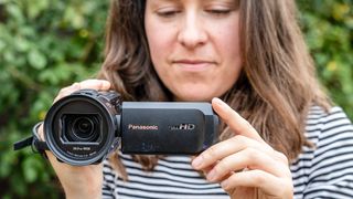 A female holding the Panasonic HC-V900 camcorder in a garden