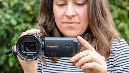 A female holding the Panasonic HC-V900 camcorder in a garden