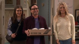 Amy, Leonard and Penny smiling in Sheldon's apartment on The Big Bang Theory