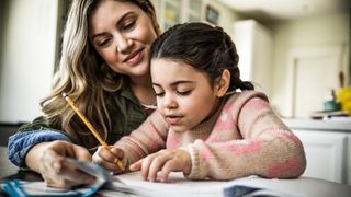 Mother and daughter (7 years) doing homework at table.