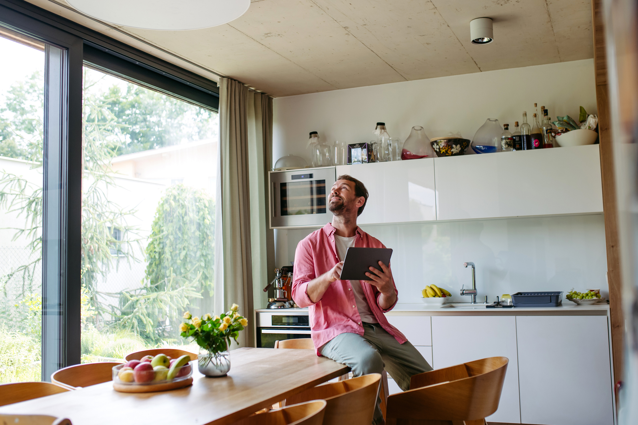 Handsome man adjusting smart home settings on touch screen device. Smart home technology for sustainable living.