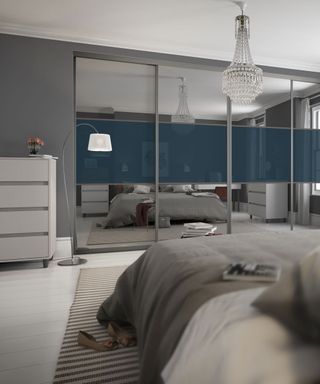 a white and grey bedroom with mirrored room dividers with blue panel across the middle and a crystal chandelier hanging from the ceiling