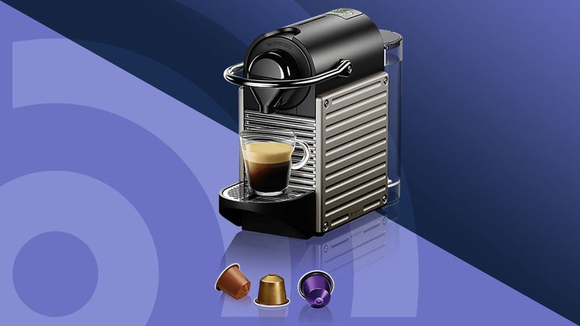 Nespresso Pixie by Krups machine with three coffee capsules on purple background