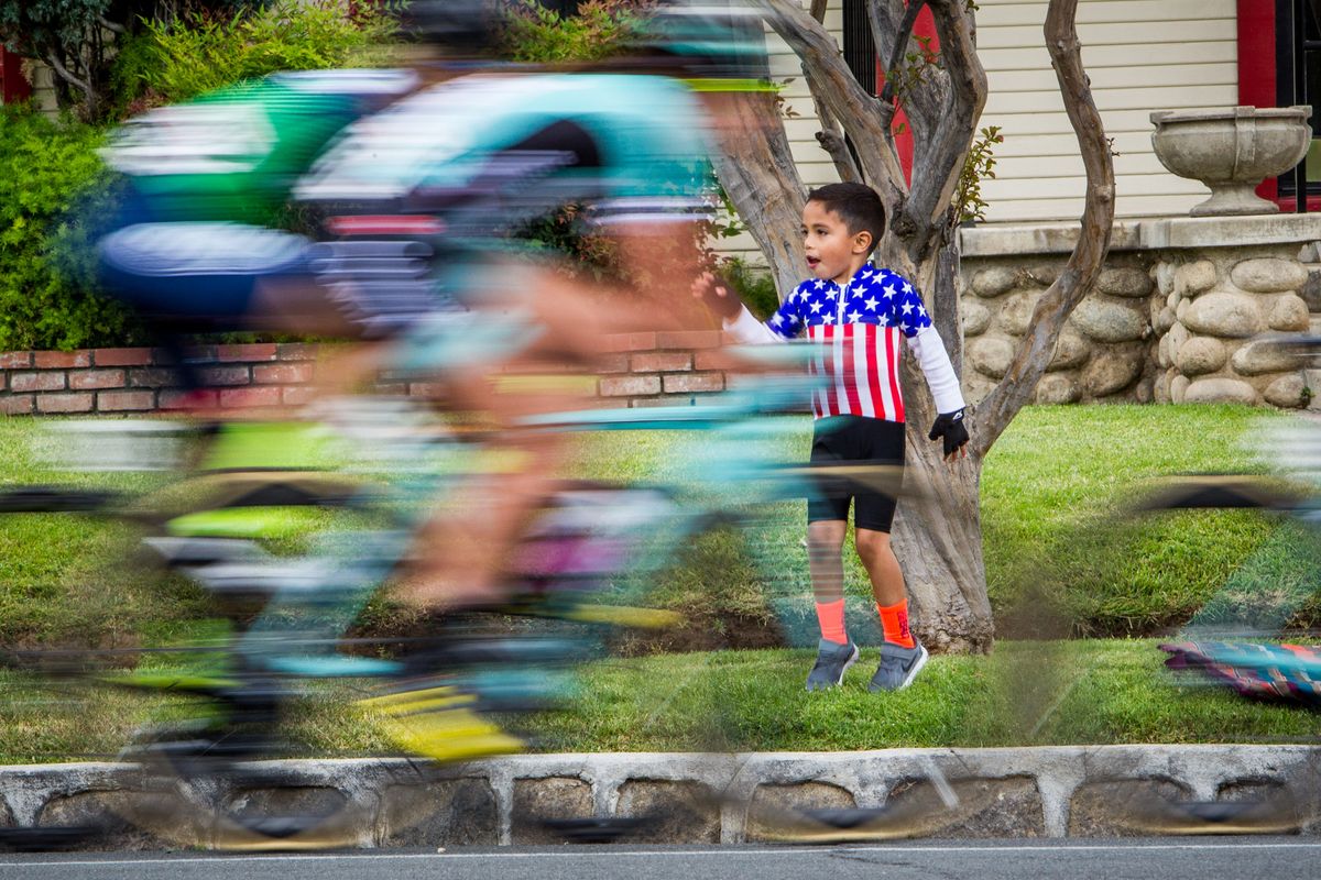 A young fan cheers as the riders pass by. }