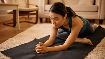 Woman doing pigeon pose stretch on the floor