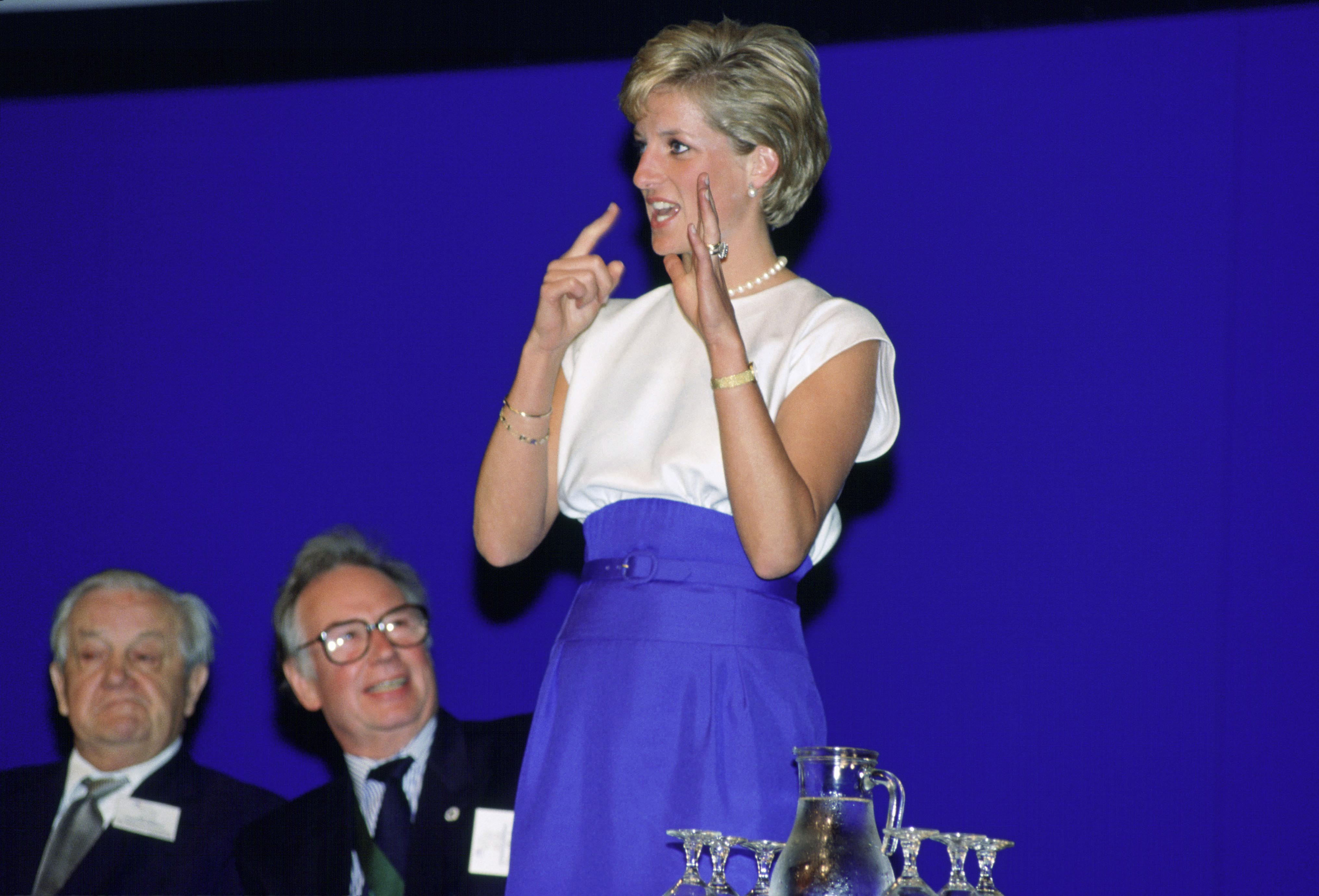 Princess Diana wearing a blue and white dress using sign language