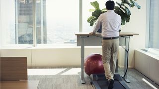 Should I buy an under desk treadmill? image shows man using under desk treadmill in office