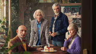 Helen Mirren, Pierce Brosnan, Ben Kingsley and Celia Imrie sit around a table with a slice of cake that has a knife in it at the center