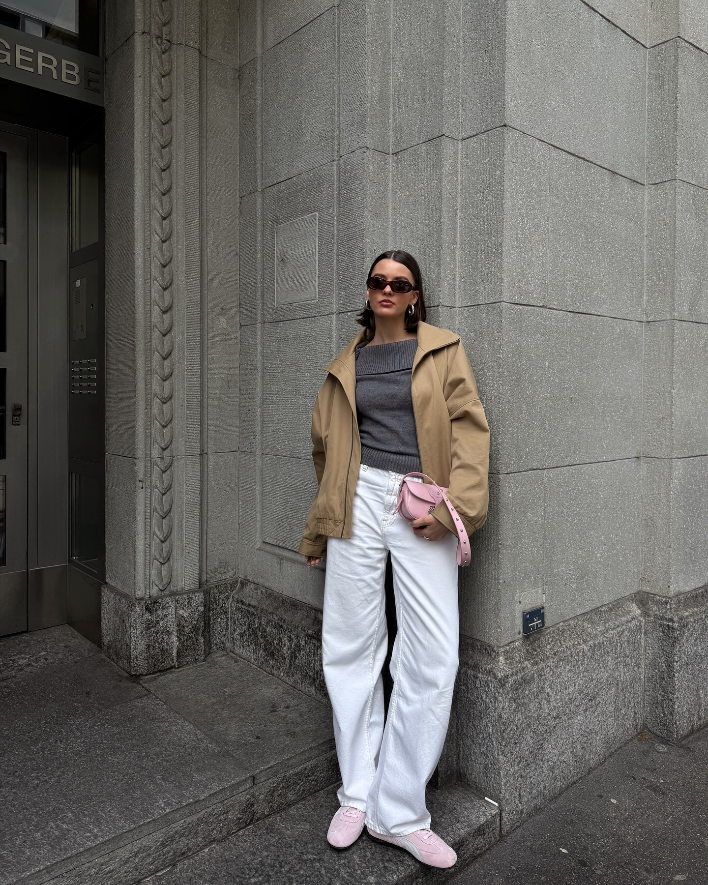 @maryljean wearing white jeans, brown jacket, grey sweater, and pink Puma sneakers