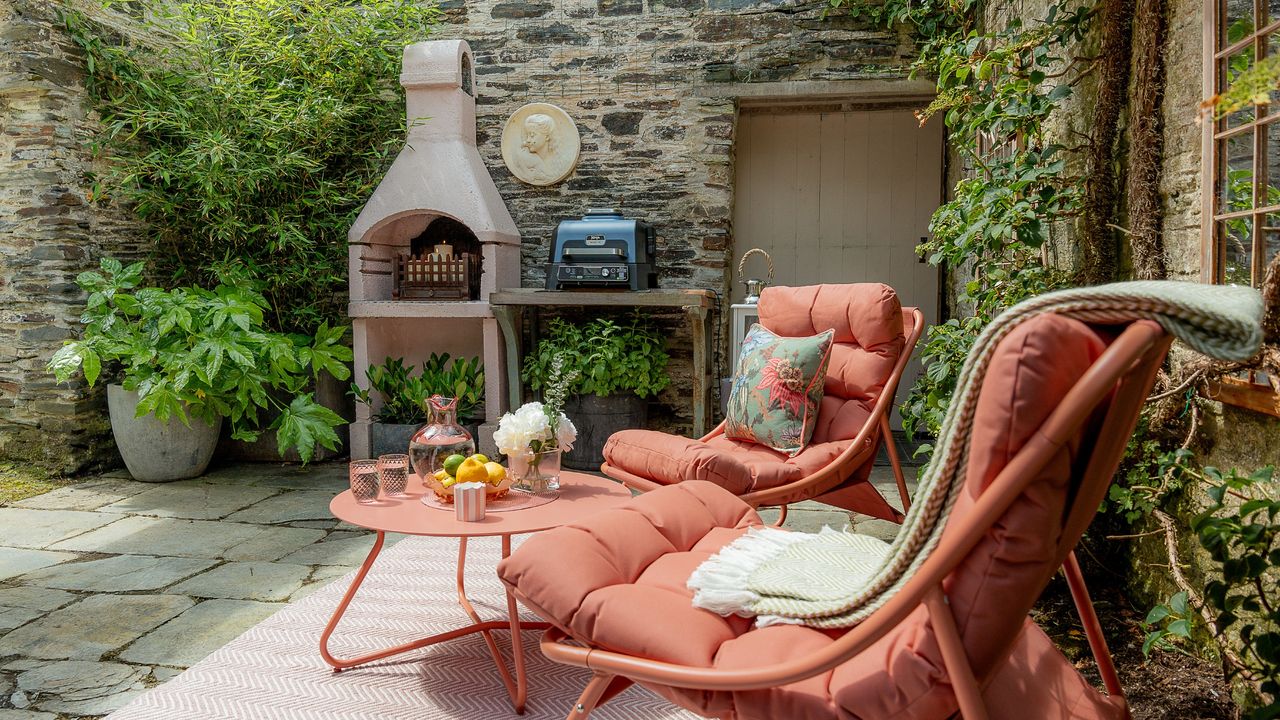 Pink seating area with loungers, coffee table and rug in Anouska Lancaster&#039;s walled garden outdoor kitchen area