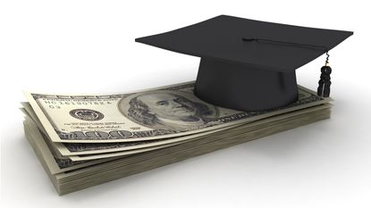 A mortar board sits on top of a stack of cash.