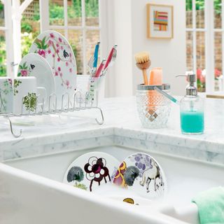 Dirty dishes in kitchen sink next to white marble kitchen counter