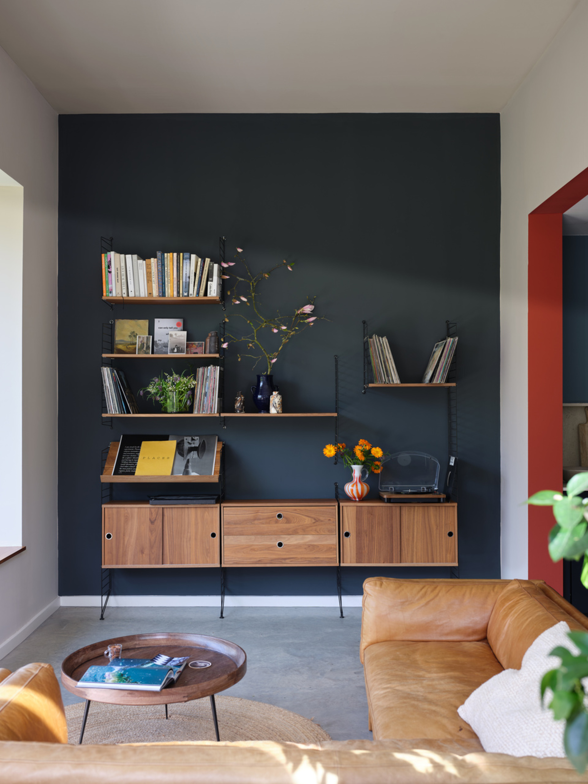A small living room with a dark blue accent wall and a red accented walkway